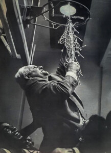 William H. Hinton, first president, celebrates on court by cutting down a basketball net as a joyful crowd gathers below.