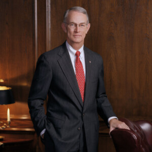 Edward D. Hodo, second president, stands by a brown leather chair in a wood-paneled academic office.