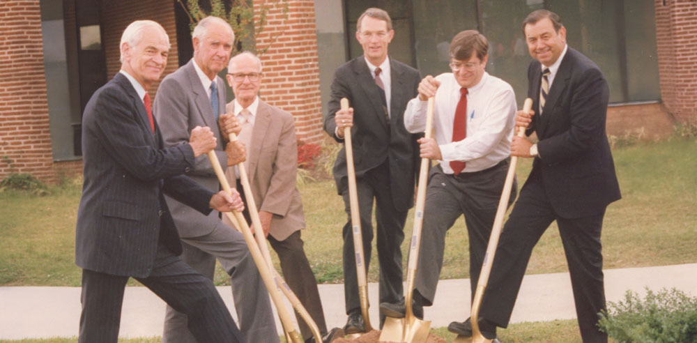 Six men in suits, including HCU’s Second President Edward D. Hodo, hold shovels at a groundbreaking on the HCU campus.