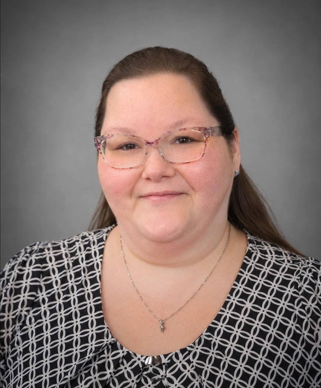 Smiling Jennifer Martin with glasses in a patterned black and white top providing academic support against a gray background.