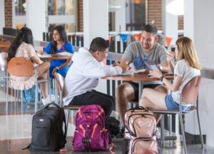 Students sitting on chairs and tables in the upper floor of Brown complex