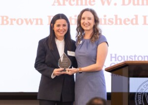 Two alumni hold an award at a Houston Christian University business networking event.