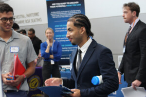 Students in business professional attire networking at a university career fair.