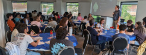 Students engage in a seminar on Student Counseling Services at round tables in a bright, modern classroom.