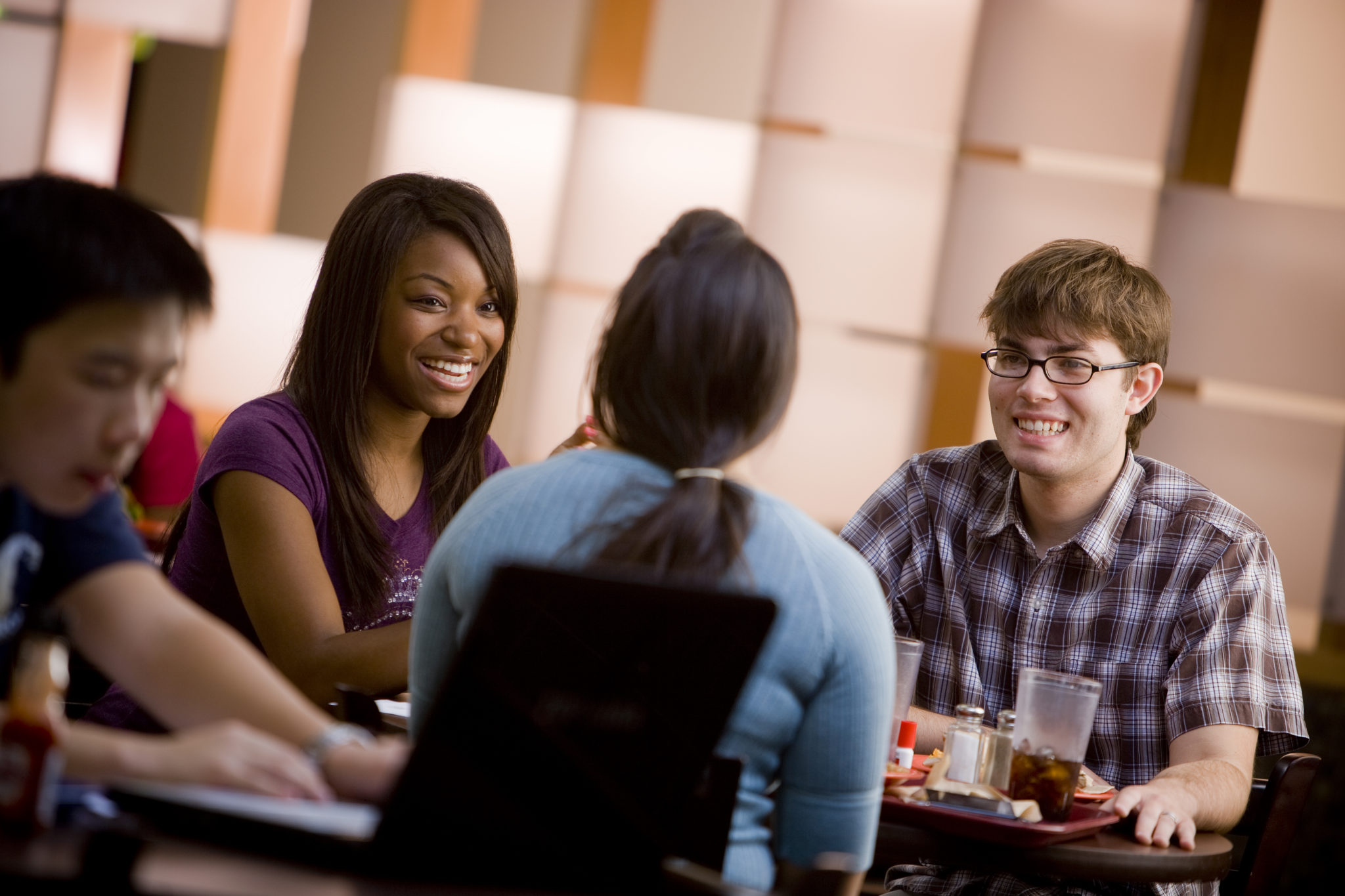Students sitting on round table in the cafeteria. 
