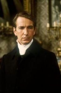 Theater student in period costume with a high white collar performs indoors, reflecting a dramatic scene akin to The Barchester Chronicles.