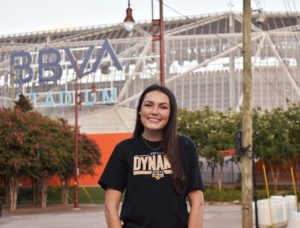 Brielle Eskridge in Houston Christian Huskies shirt with an Accounting Degree stands outside HCU campus on a sunny day.