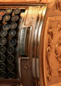Ornate vintage cash register displayed in a museum exhibit, highlighting historical craftsmanship and detail.