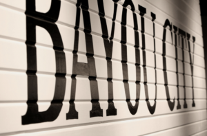 BAYOU CITY in bold black letters on a white wall inside HCU, photographed at an angle for clear, high-contrast visibility.