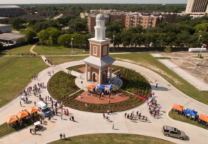 HCU campus view featuring Belin Tower during the 60th Anniversary, with crowds, tents, and lush greenery along walkways.