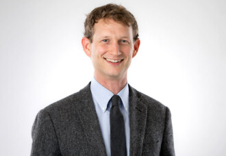 Dr. Paul T. Sloan, smiling in suit and tie, stands before a plain white backdrop; recognized book award recipient.