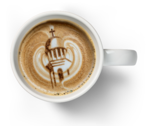 Coffee cup with latte art depicting Belin Chapel’s dome and cross from above, inspired by HCU campus architecture.
