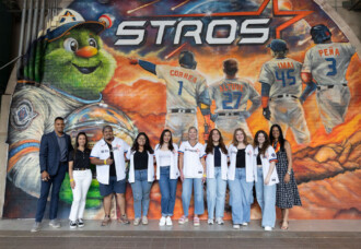MFA students in Astros jerseys pose before mural of Astros players and mascot, celebrating Astros Opening Day on HCU campus.