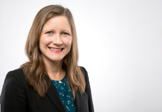 Shannon Bedo, Texas State Award recipient, smiles in black blazer and teal blouse against a plain white academic backdrop.