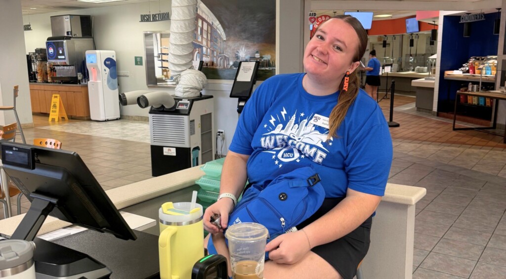 Sophia, a student worker in a blue HCU t-shirt, at the Student Center dining hall check-in desk.