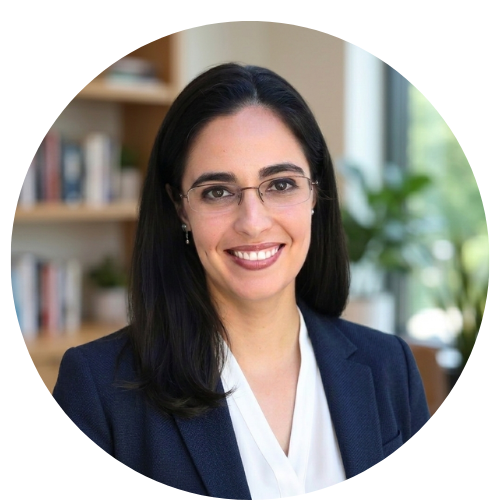 Smiling adjunct faculty with long dark hair, glasses, and blazer in a book-lined academic office.