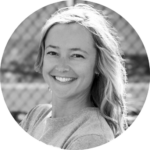 Smiling woman with long hair in a casual shirt outdoors at the Narrative Arts Conference on HCU campus, blurred fence behind her.