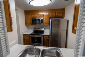 University Place apartment kitchen with wooden cabinets, stainless appliances, stove, microwave, fridge, and double sink.