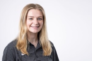 Smiling young woman with long blonde hair wears a striped shirt, welcoming students as part of Residence Life at Houston Christian University.