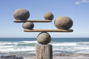 round and flat rocks balancing on top of each other on top on a would stump on a beach.