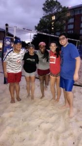 Students on the beach volleyball court at night