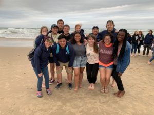 12 HCU students posing for a photo by the beach
