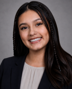 Smiling woman with long dark hair in a suit jacket, posing for a professional profile related to human resource management at HCU.