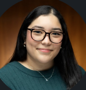Smiling woman with long dark hair, glasses, and a green sweater at Houston Christian University representing human resources.