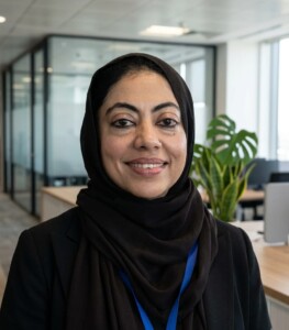 Woman in a black hijab smiling in a bright office, embodying professional excellence in human resource management studies.