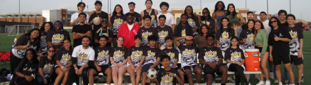 Filipino students in matching shirts gather on HCU campus soccer field, smiling together on a sunny day.