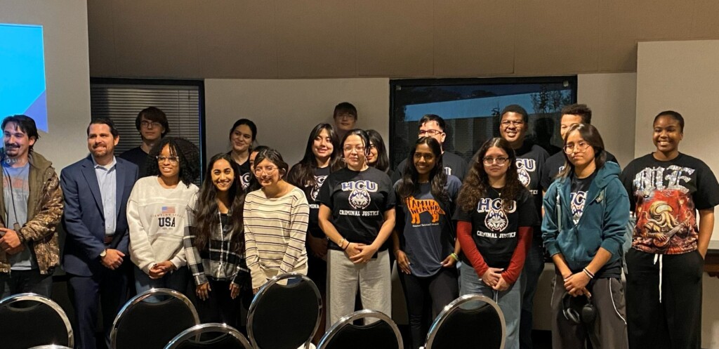 Supporters smiling for a photo during a campus meeting; empty chairs visible in the foreground.