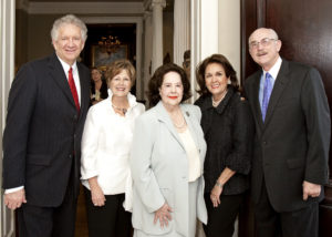 Group of five adults in formal wear smiling at a Silver Teas event, gathered indoors for an academic celebration.
