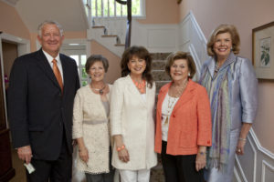 Five adults in business casual attire share a warm moment, reflecting the camaraderie typical at Houston Christian University.