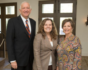 Two women and a man smiling at a Guild Fall Coffee event indoors, wearing business and casual attire, academic setting.