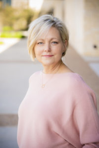 Tonya Riggle with short blonde hair in a pink top enjoying the Guild Christmas Luncheon outdoors on HCU campus.