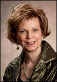 Kandy Brittain with short, styled light brown hair in a green patterned jacket and earrings, honoring Past Presidents.