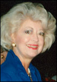 Lou Davis with short white hair in a blue top and pearl earrings, at event honoring Past Guild Presidents indoors.