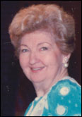 Lee Lawrence with short wavy hair, smiling in blue patterned top and pearls, honors Past Guild Presidents at university event.