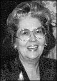 Mary Olsen with glasses in a patterned jacket, recognized for leadership among past presidents. Black and white indoor portrait.
