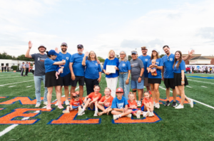 A group posing on the Houston Christian University campus football field during the Family of the Year award recognition.