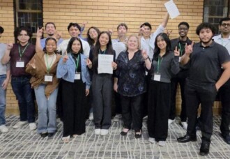 Students at the Iota Omicron regional convention indoors, smiling and displaying awards during an academic event.